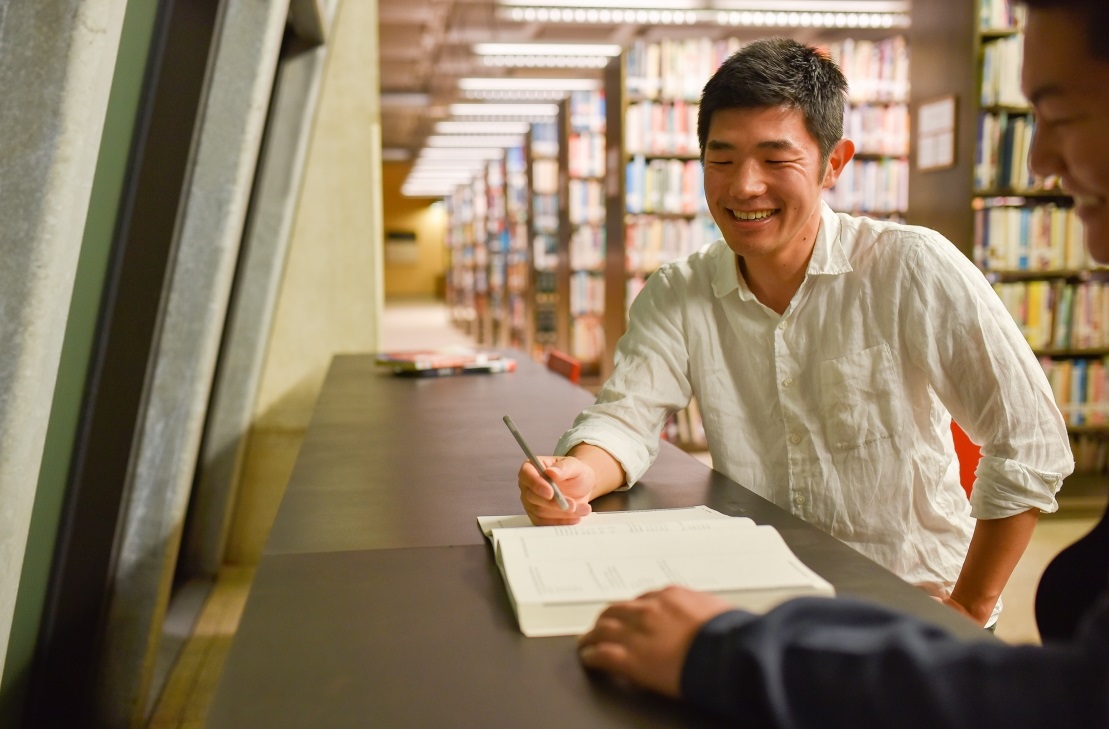 Photo of Take Morikawa tutoring a student at a library